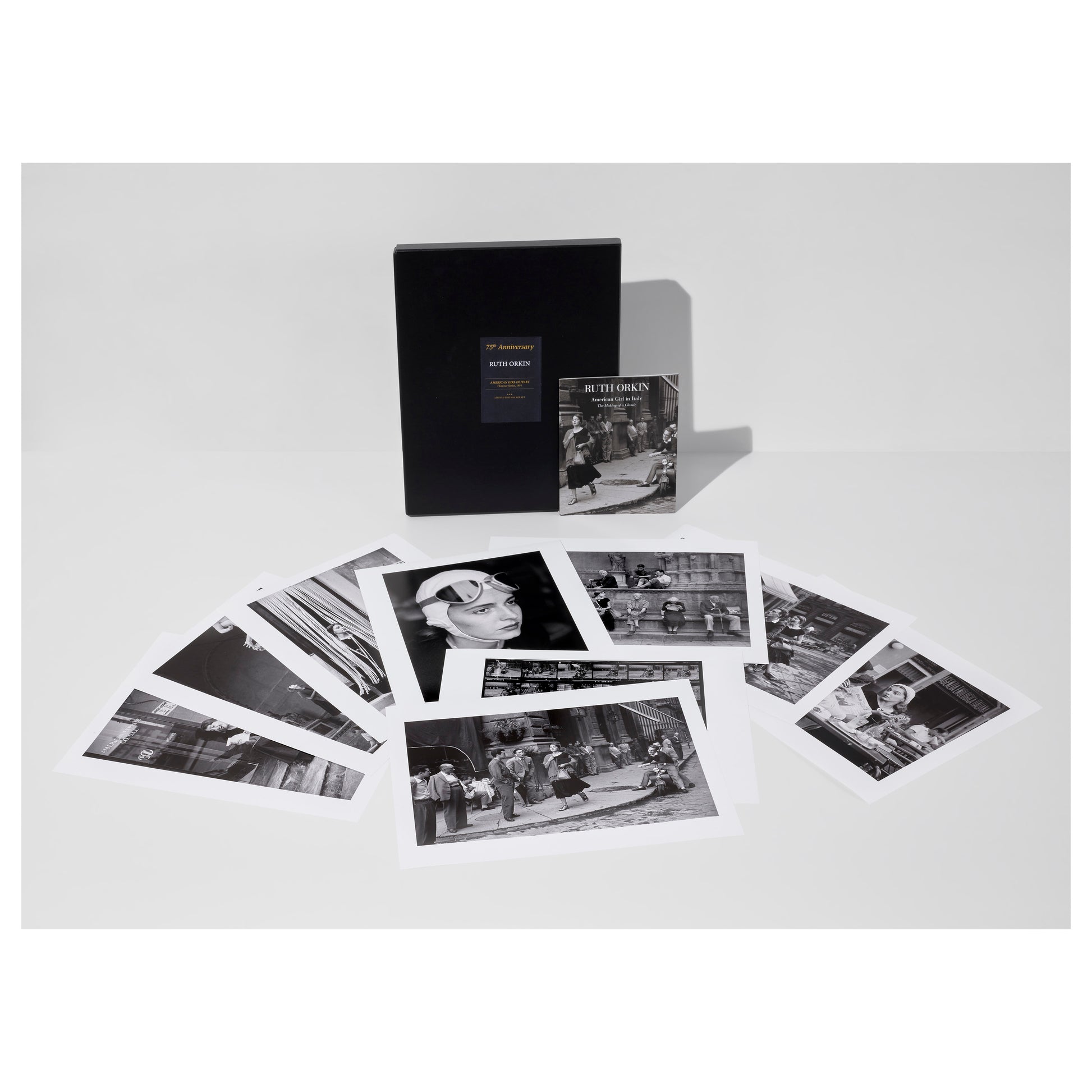 Collection of black and white Ruth Orkin photos from American Girl in Italy, a portfolio box, and an exhibition catalogue on a light gray background