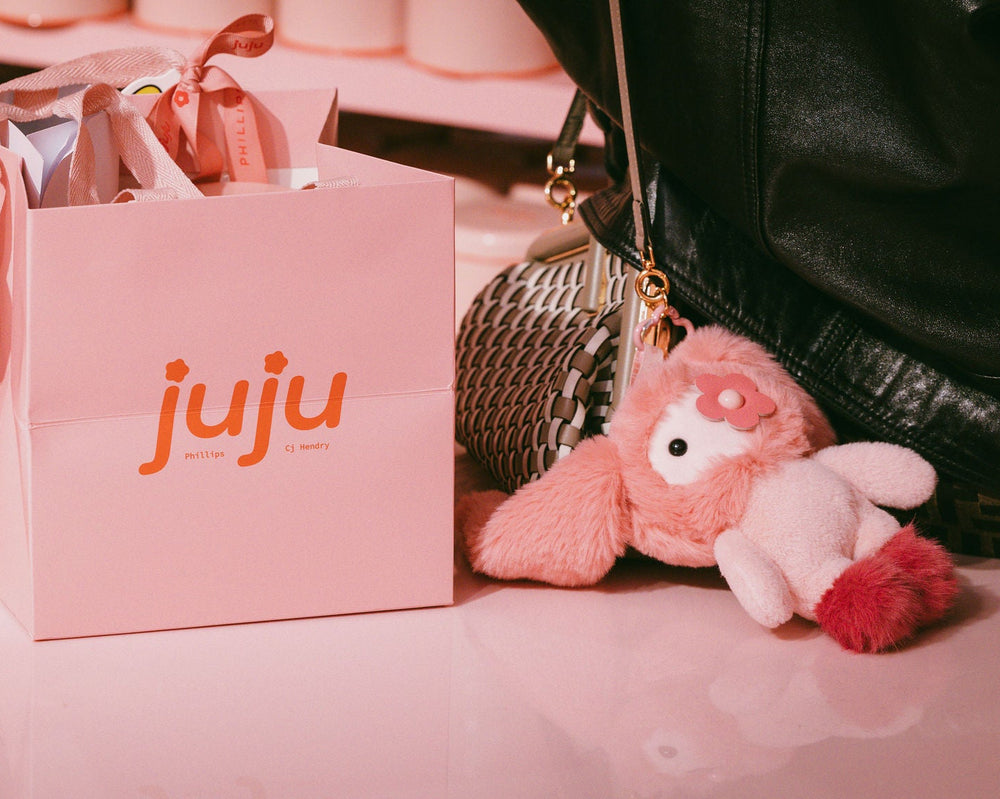 Pink 'juju' bags with a plush toy on a pink surface. CJ HENDRY. Dropshop by Phillips